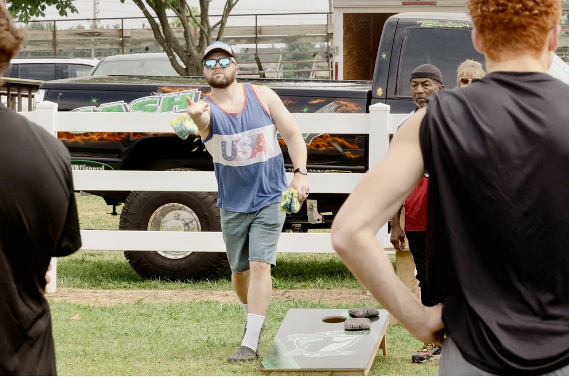 a man throws a bag in a corn hole tournament